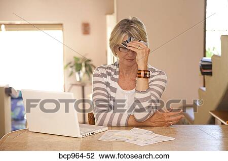 Stock Image - Woman at home office with credit cards. Fotosearch