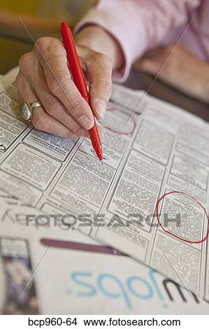 Picture - Woman circling employment ads in paper. Fotosearch