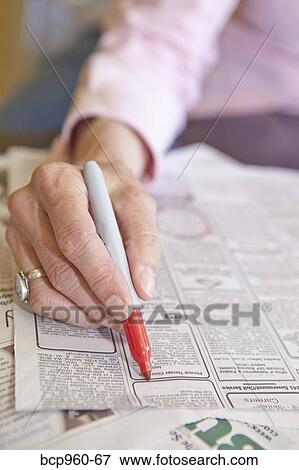 Stock Photo - Woman circling employment ads in paper. Fotosearch