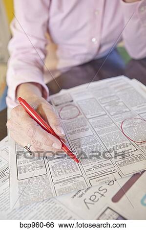 Stock Photograph - Woman circling employment ads in paper. Fotosearch