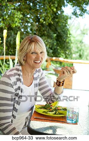 Stock Image - Woman eating salad outdoors. Fotosearch