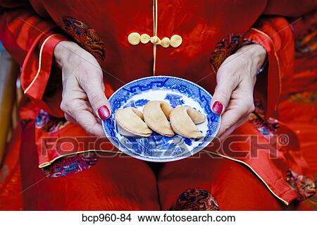 Picture - Woman holding plate of fortune cookies. Fotosearch