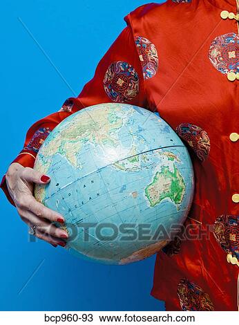 Stock Image - Woman in Chinese pajamas holding globe. Fotosearch