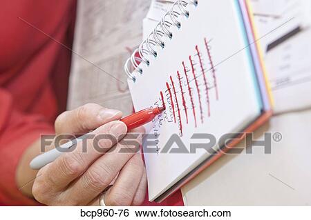 Stock Photograph - Woman making list in small notebook. Fotosearch