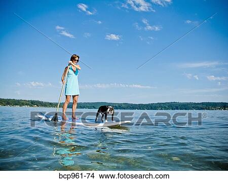 Picture - Woman on paddle board with dog. Fotosearch