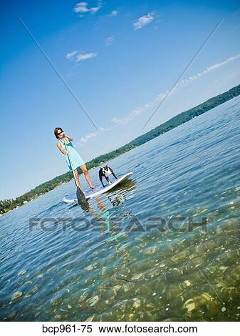 Stock Photography - Woman on paddle board with dog. Fotosearch