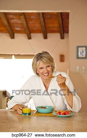 Woman seated at counter eating healthy breakfast View Large Photo Image Stock Photo - Woman seated at counter eating healthy breakfast. Fotosearch