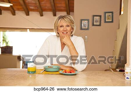 Woman seated at counter eating healthy breakfast View Large Photo Image Stock Photograph - Woman seated at counter eating healthy breakfast. Fotosearch