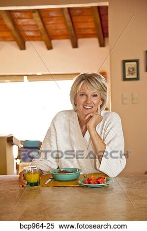 Woman seated at counter eating healthy breakfast View Large Photo Image Stock Photography - Woman seated at counter eating healthy breakfast. Fotosearch