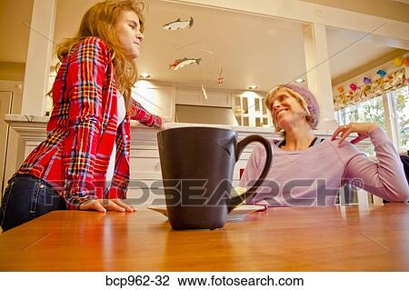 Woman seated at dining table talking with teen girl View Large Photo Image Stock Image - Woman seated at dining table talking with teen girl. Fotosearch