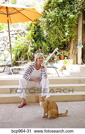 Woman seated on patio steps with orange cat View Large Photo Image Stock Image - Woman seated on patio steps with orange cat. Fotosearch