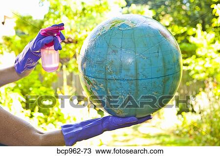 Stock Image - Woman wearing rubber gloves to clean globe outdoors. Fotosearch