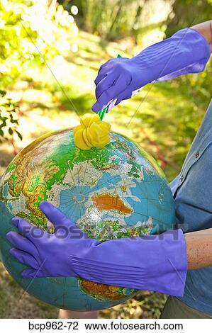Stock Image - Woman wearing rubber gloves to scrub globe outdoors. Fotosearch