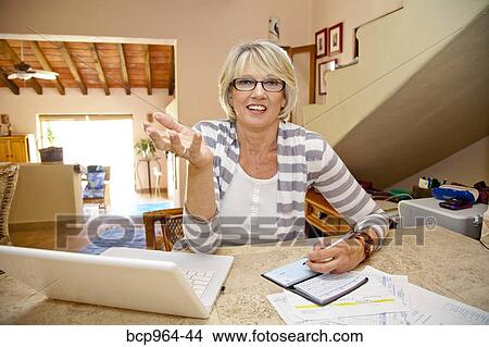 Woman working at home office with computer and bills View Large Photo Image Picture - Woman working at home office with computer and bills. Fotosearch