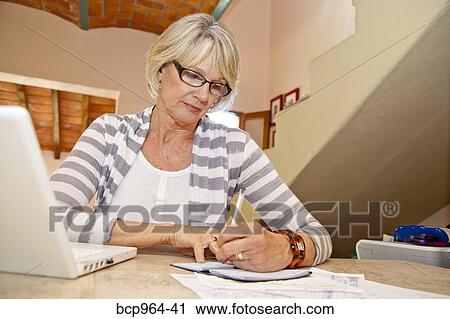Woman working at home office with computer and bills View Large Photo Image Stock Image - Woman working at home office with computer and bills. Fotosearch