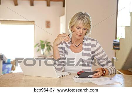 Woman working at home office with computer and bills View Large Photo Image Stock Photo - Woman working at home office with computer and bills. Fotosearch