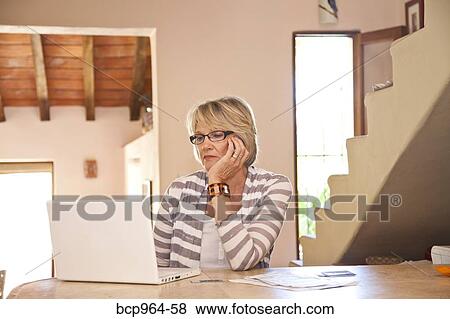 Woman working at home office with computer and bills View Large Photo Image Stock Photo - Woman working at home office with computer and bills. Fotosearch