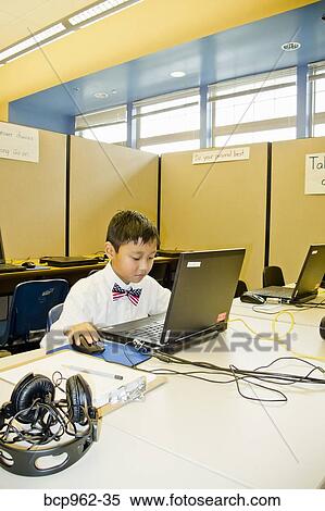 Stock Photography - Young boy seated at school laptop in computer lab. Fotosearch