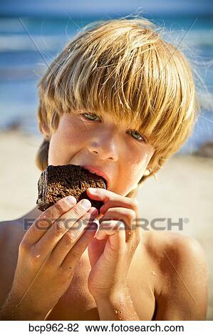 Young boy taking bite of large brownie View Large Photo Image Stock Image - Young boy taking bite of large brownie. Fotosearch