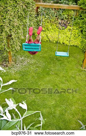 Stock Image - Boy on backyard swing. Fotosearch