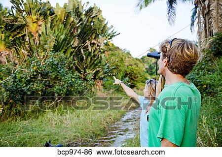 Stock Photograph - Couple birdwatching in jungle. Fotosearch