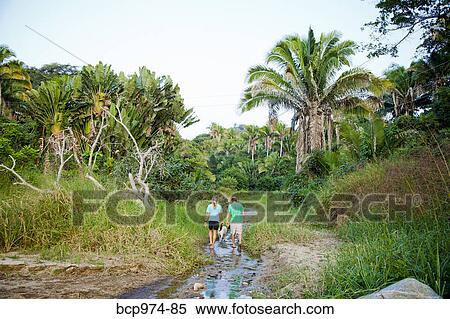 Stock Photography - Couple hiking in jungle stream bed. Fotosearch