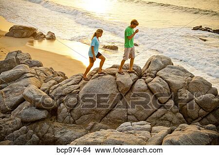Picture - Couple hiking on beach rocks. Fotosearch