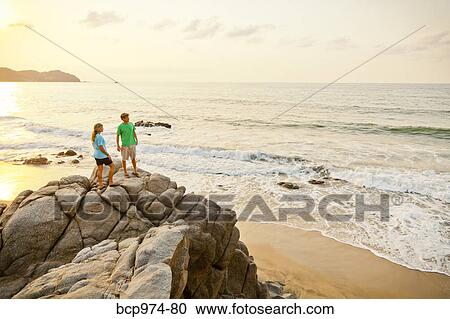 Couple hiking on beach rocks View Large Photo Image Stock Image - Couple hiking on beach rocks. Fotosearch