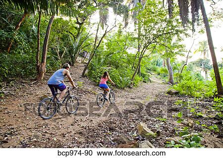 Couple riding bicycles on jungle path View Large Photo Image Stock Image - Couple riding bicycles on jungle path. Fotosearch