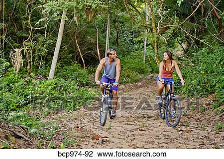 Couple riding bicycles on jungle path View Large Photo Image Stock Image - Couple riding bicycles on jungle path. Fotosearch
