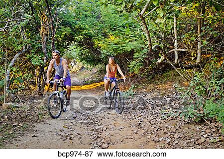 Couple riding bicycles on jungle path View Large Photo Image Stock Photo - Couple riding bicycles on jungle path. Fotosearch