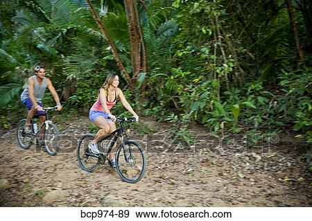 Couple riding bicycles on jungle path View Large Photo Image Stock Photo - Couple riding bicycles on jungle path. Fotosearch