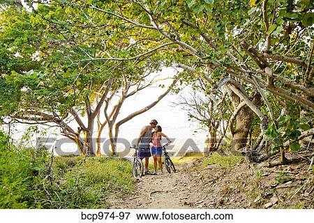 Couple riding bicycles on path to beach View Large Photo Image Stock Photo - Couple riding bicycles on path to beach. Fotosearch
