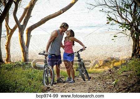 Couple riding bicycles on path to beach View Large Photo Image Stock Photo - Couple riding bicycles on path to beach. Fotosearch