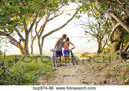 Stock Photograph - Couple riding bicycles on path to beach. Fotosearch