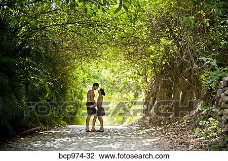 Stock Image - Couple walking down tree arched path. Fotosearch
