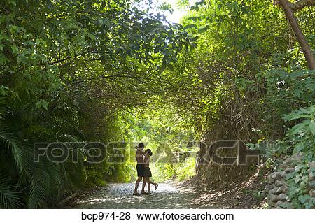 Stock Photo - Couple walking down tree arched path. Fotosearch