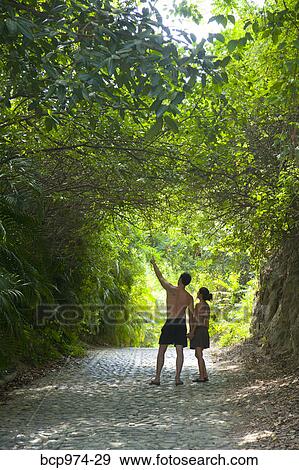 Stock Photo - Couple walking down tree arched path. Fotosearch