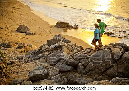 Couple with dog hiking on beach rocks View Large Photo Image Stock Image - Couple with dog hiking on beach rocks. Fotosearch