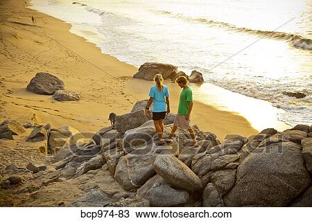 Couple with dog hiking on beach rocks View Large Photo Image Stock Image - Couple with dog hiking on beach rocks. Fotosearch