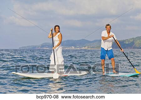 Dressed up man and woman riding paddle boards View Large Photo Image Stock Photo - Dressed up man and woman riding paddle boards. Fotosearch