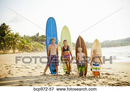 Stock Photo - Family standing on beach with surfboards. Fotosearch