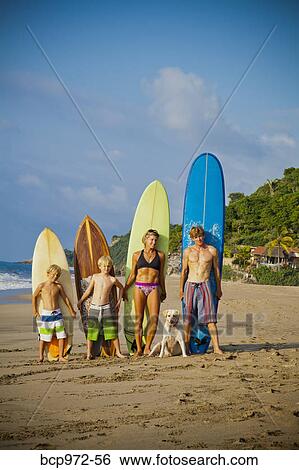 Stock Photograph - Family standing on beach with surfboards. Fotosearch