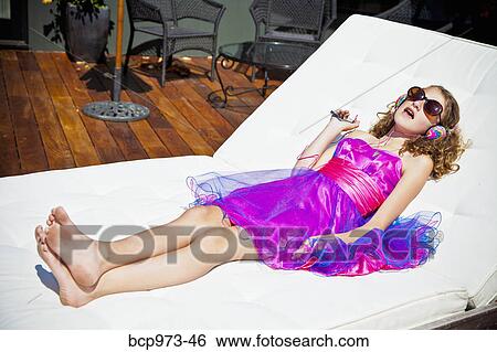 Stock Photograph - Girl in party dress lounging and listening to music. Fotosearch