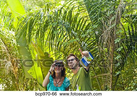 Man and woman bird watching in jungle View Large Photo Image Stock Photograph - Man and woman bird watching in jungle. Fotosearch