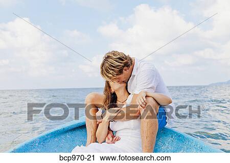 Stock Image - Man and woman embracing in bow of boat. Fotosearch