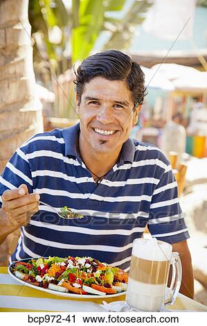 Stock Image - Man eating at outdoor caf. Fotosearch