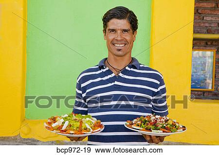 Man holding plates of mexican food View Large Photo Image Stock Photo - Man holding plates of mexican food. Fotosearch