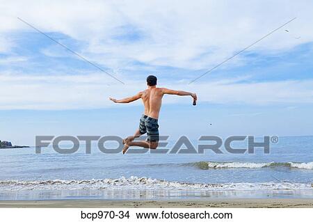 Man leaping in air on beach View Large Photo Image Picture - Man leaping in air on beach. Fotosearch