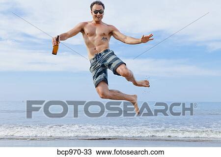 Man leaping in air on beach View Large Photo Image Stock Image - Man leaping in air on beach. Fotosearch